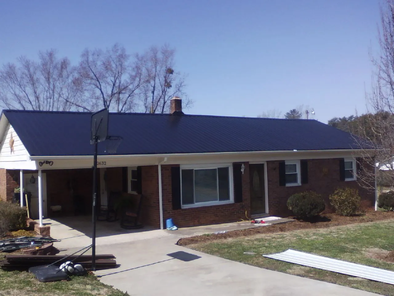Finished dark blue metal roof on a brick ranch with a carport in Clarks Hill