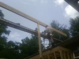 Carpenter setting a ridge beam over a new addition frame — Ice Dam Removal by Roofing Brothers in Clarks Hill