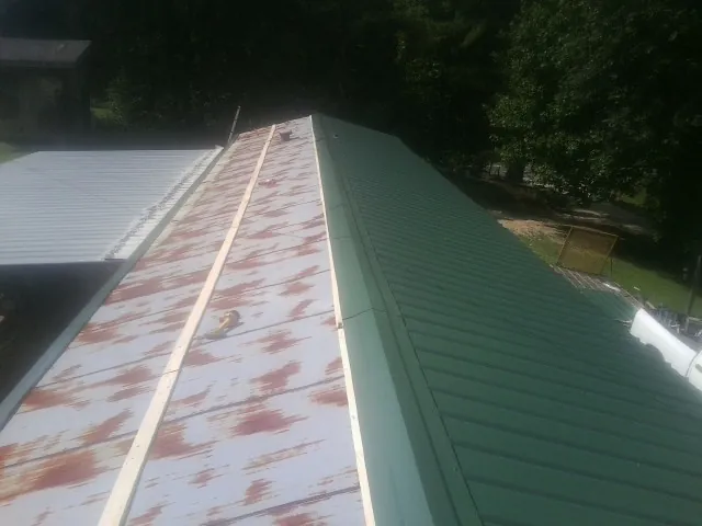 Old rusted panels beside newly installed green metal roofing — Wind Damage Roof Repair by Roofing Brothers in Clarks Hill