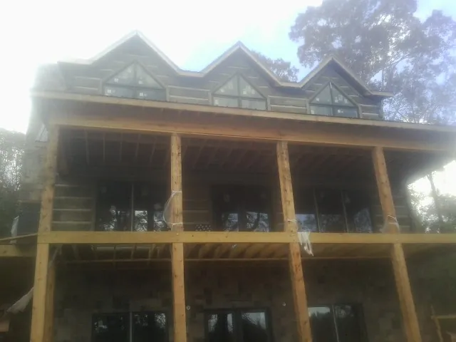 Dormers and porch framing on a large log home under construction — Roof Coating work by our crew in Clarks Hill