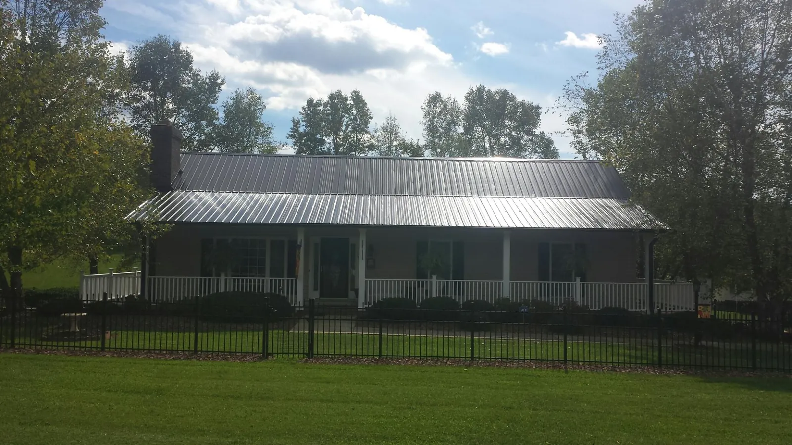 Gray metal roof on a brick ranch with a full width front porch — Gutter Guard Installation work by our crew in Clarks Hill